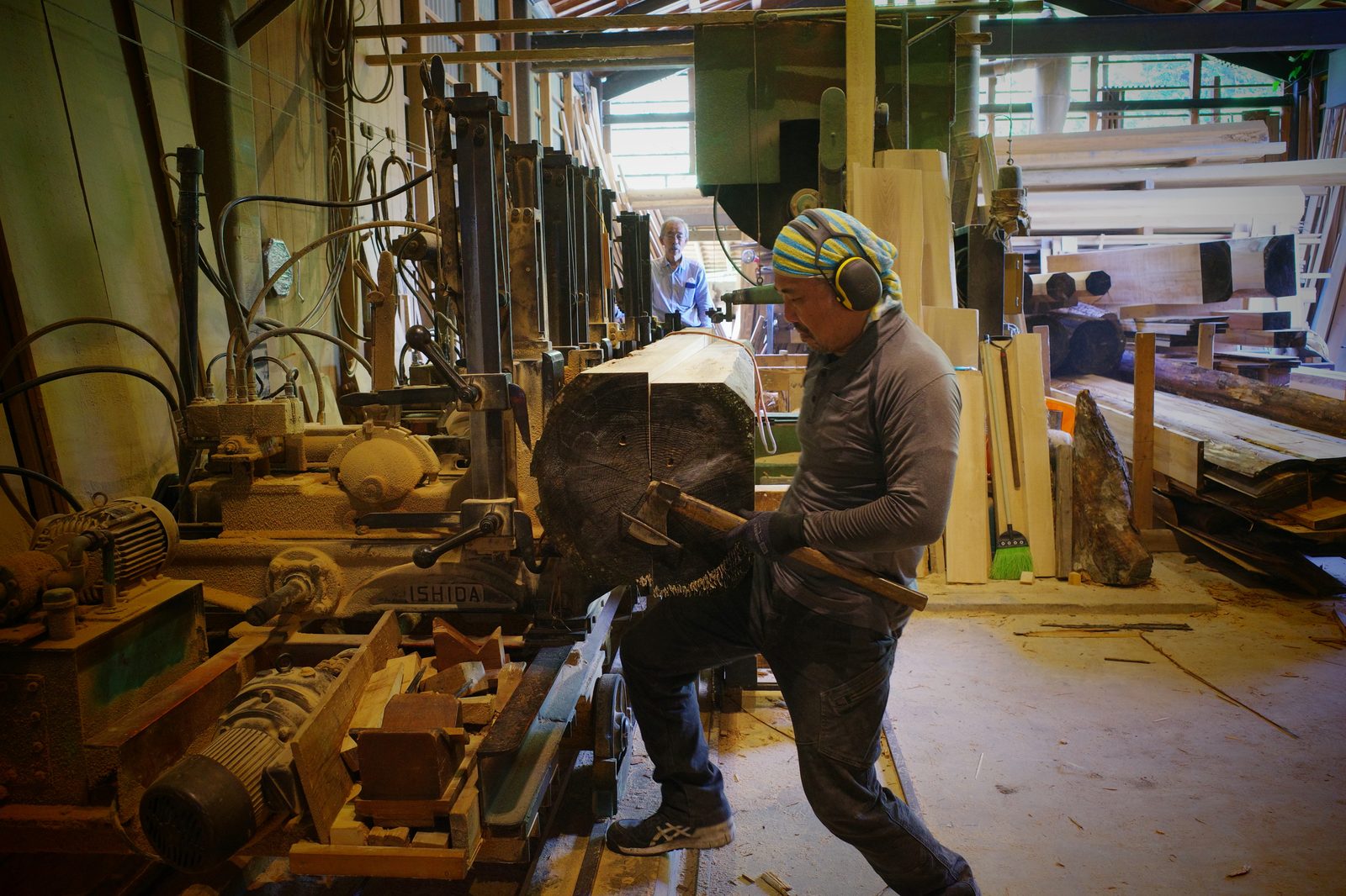 職人が製材機で原木を加工している作業風景